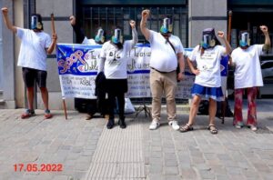 groupe de personne avec des masques et des banderoles devant un batiment